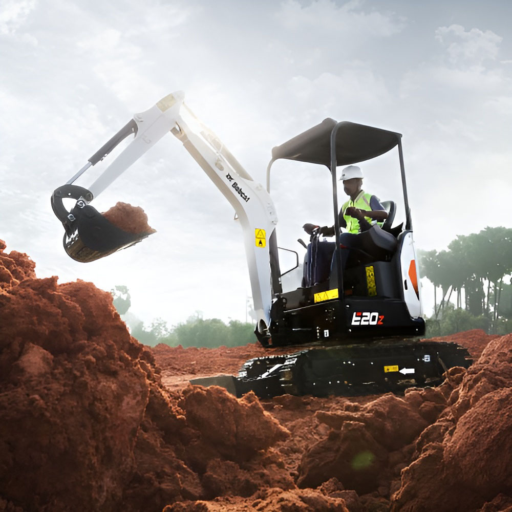 Bobcat E20z mini excavator digging red soil, operator in hi-vis
