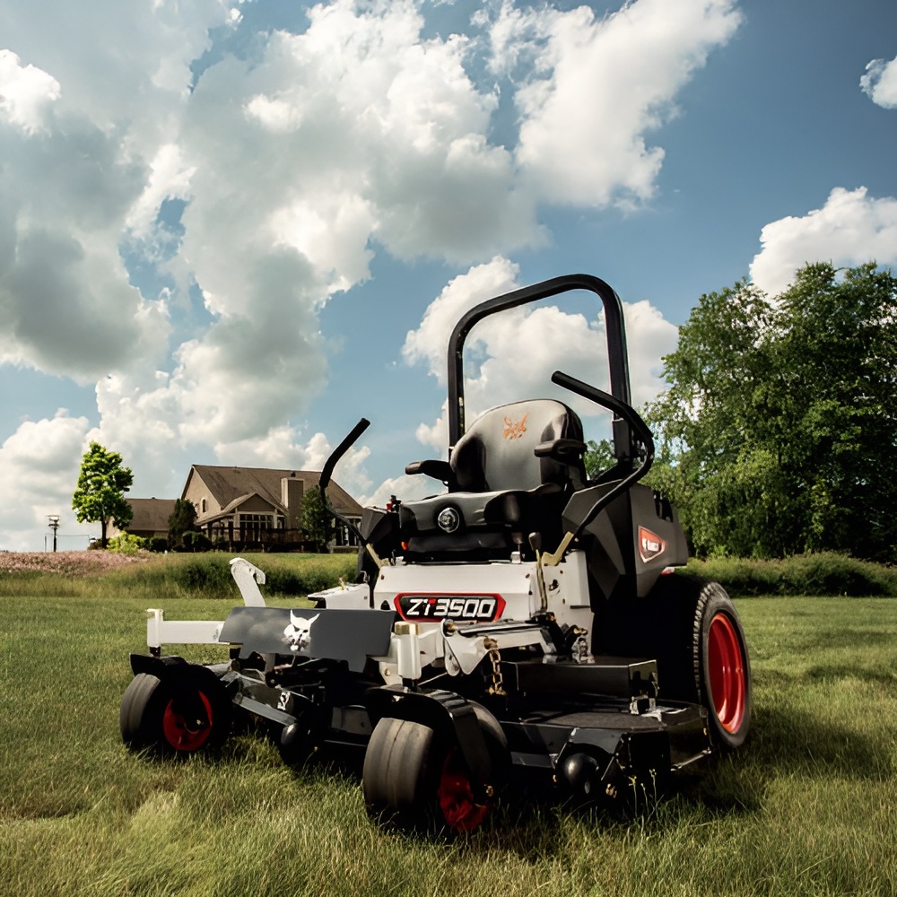 Bobcat ZT3500 zero-turn mower in long grass with houses behind